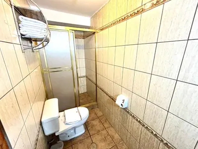 a small bathroom with a toilet and a shower at Hotel Rojas Machupicchu in Machu Picchu
