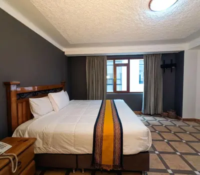 a bedroom with a bed and a window at Hotel Rojas Machupicchu in Machu Picchu