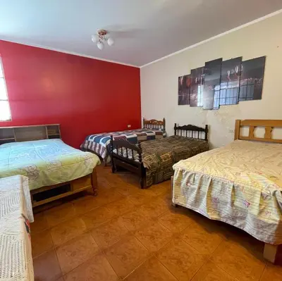 a room with two beds and a red wall at Habitación para 4 personas a pasos de la plaza de armas in Ayacucho