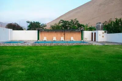 a building with chairs in a yard with a mountain at Kampu Wasi - Casa de Campo in Pachacamac