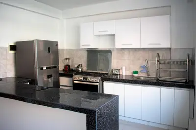 a kitchen with white cabinets and black counter tops at Kampu Wasi - Casa de Campo in Pachacamac