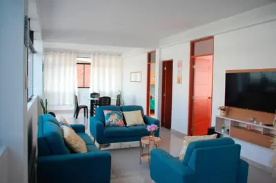 a living room with blue chairs and a flat screen tv at Kampu Wasi - Casa de Campo in Pachacamac