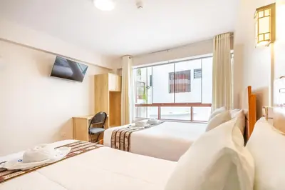 a hotel room with two beds and a window at Hostal Cusco Guest Home in Cusco