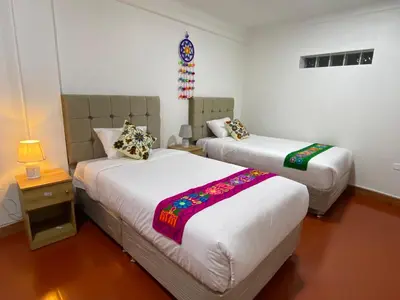 a bedroom with two beds and a night stand with a lamp at Wayna Boutique Hotel in Cusco