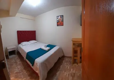 a small bedroom with a bed with a red headboard at Hospedaje M&M in Cusco