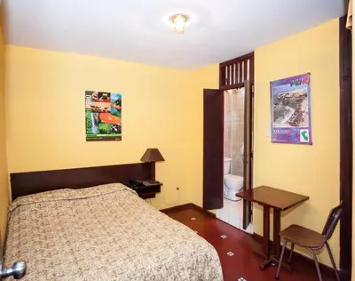 a bedroom with a bed and a table and a desk at Hostal Iquique in Lima