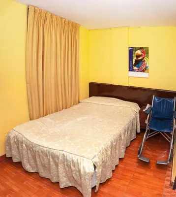 a bedroom with a bed and a blue chair at Hostal Iquique in Lima