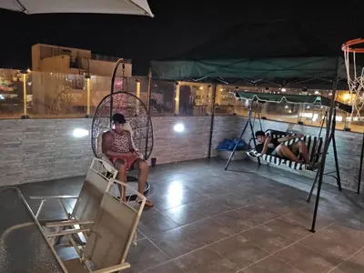 a couple of people sitting on swings at night at Departamento en Playa San Bartolo Con terraza in San Bartolo