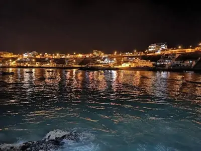 a large body of water with a city at night at Departamento en Playa San Bartolo Con terraza in San Bartolo
