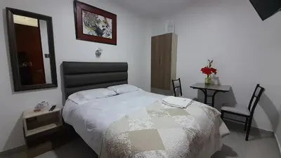 a bedroom with a bed and a table and a chair at La Rinconada de Churin in Churín