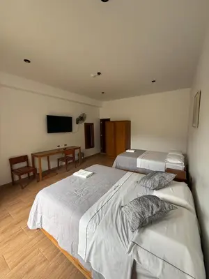 a bedroom with two beds and a desk and a tv at The Wismont club & hotel in La Merced