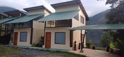 a house with green roof and mountains in the background at Ecoterra Inka Lodge in Quillabamba