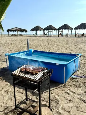 a blue boat sitting on the beach with a grill at Bungalows en playa Wakama in San Vicente de Cañete