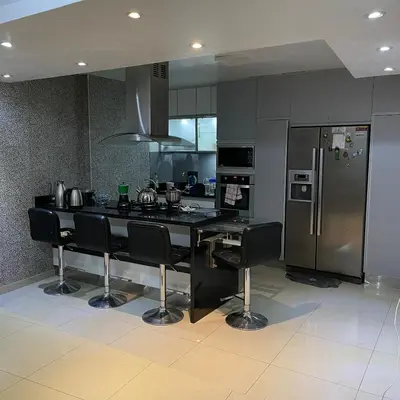 a kitchen with black counter chairs and a refrigerator at Casa La warida con tres niveles in Ayacucho