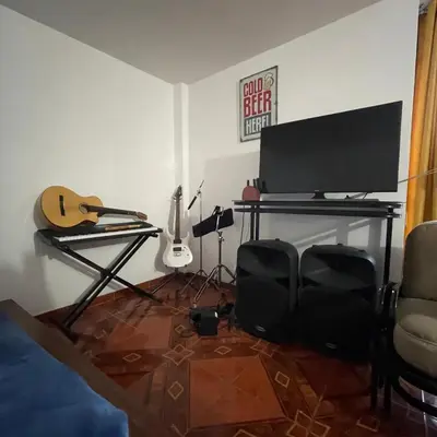a room with a desk with a television and a guitar at Casa La warida con tres niveles in Ayacucho