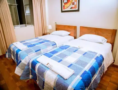 two beds in a hotel room with towels on them at Hotel Wismont Piñales in La Merced