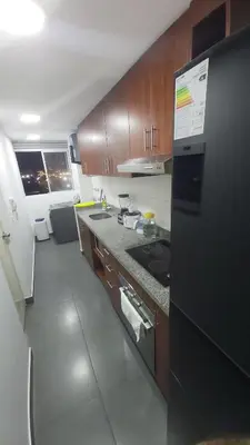 a kitchen with wooden cabinets and a black refrigerator at Departamento con Vista al Mar San Miguel in Lima