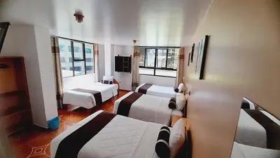a hotel room with three beds and windows at El Tambo Machupicchu in Machu Picchu