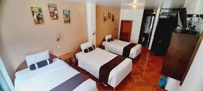 a room with two beds and a television in it at El Tambo Machupicchu in Machu Picchu