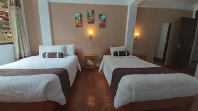 a hotel room with two beds with white sheets at El Tambo Machupicchu in Machu Picchu