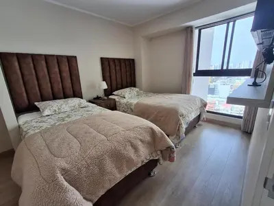 a bedroom with two beds and a large window at Departamento de estreno en San Isidro in Lima