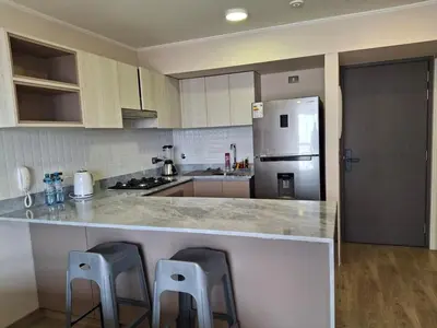 a kitchen with a counter with two stools and a refrigerator at Departamento de estreno en San Isidro in Lima