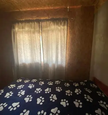 a bed with a blue comforter and a window at Casa de campo Miraflores in Oxapampa
