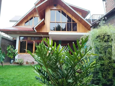 a house with a wooden roof and a green yard at Casa de Machi in Villa Rica