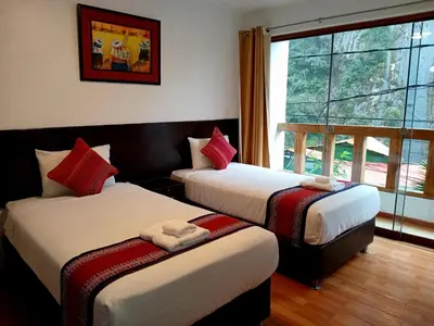 two beds in a room with a window at El Quetzal MachuPicchu in Machu Picchu