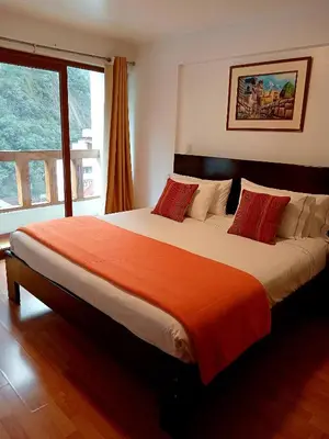 a bedroom with a large bed with an orange blanket at El Quetzal MachuPicchu in Machu Picchu