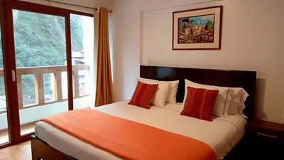 a bedroom with a bed with red pillows and a window at El Quetzal MachuPicchu in Machu Picchu