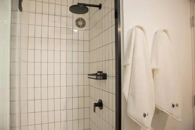 a shower with white tiled walls and white towels at Arrieta by Wynwood House in Lima