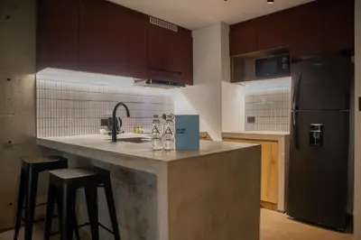 a kitchen with a counter with stools and a refrigerator at Arrieta by Wynwood House in Lima