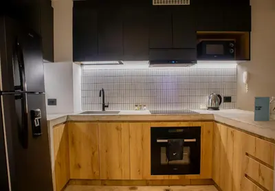 a kitchen with wooden cabinets and a sink and a refrigerator at Arrieta by Wynwood House in Lima