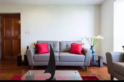 a living room with a gray couch with red pillows at Apartamento en Miraflores in Lima