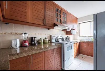 a kitchen with wooden cabinets and a white stove top oven at Apartamento en Miraflores in Lima