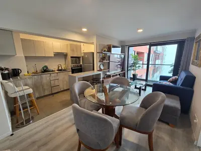 a living room with a table and chairs and a kitchen at Departamento con vista al mar en Lima in Lima