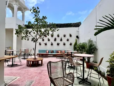 a patio with tables and chairs and a white wall at Andara Boutique Hotel in Lima