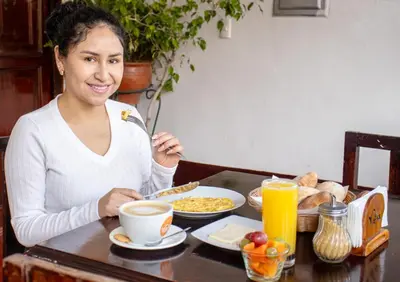 a woman sitting at a table with a plate of food at ViaVia Ayacucho in Ayacucho