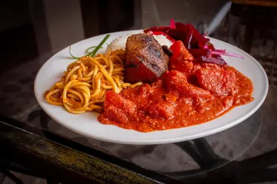 a plate of spaghetti and meat on a glass table at ViaVia Ayacucho in Ayacucho