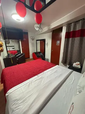 a bedroom with a bed with red sheets and balloons at Hospedaje Winikunka in Lima