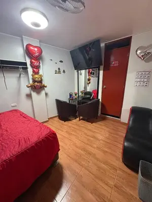 a bedroom with a red bed and a living room at Hospedaje Winikunka in Lima