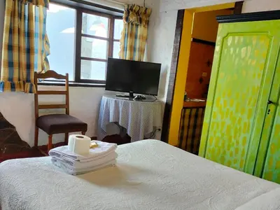 a bedroom with a bed and a tv and a chair at Casa del Gringo in Cieneguilla