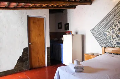 a room with a refrigerator and a bed and a door at Casa del Gringo in Cieneguilla
