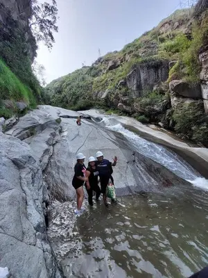 three people walking through the water in a river at Restobar & Hotel Campestre Aisha in Cocachacra