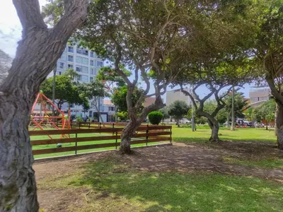 a park with trees and a bench and a playground at Cozy Apartment for Tourist in Lima