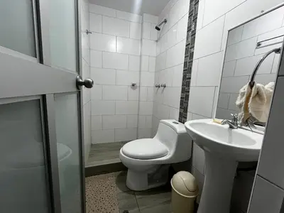 a white bathroom with a toilet and a sink at Departamento Centro Histórico in Ayacucho