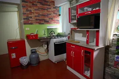 a small kitchen with red cabinets and a sink at Casa Secretos in Cusco