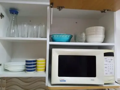 a microwave in a kitchen with bowls and plates at Departamento en Centro de Lima - Santa Beatriz in Lima