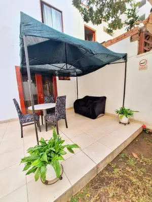 a patio with a table and chairs and an umbrella at Casa Villa Descanso in Lima